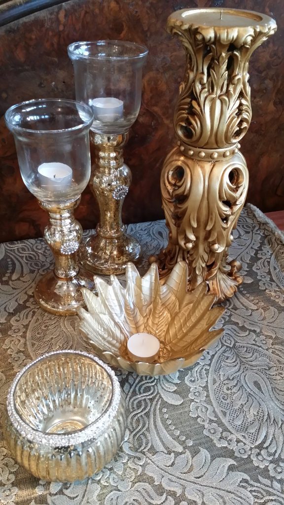 A close up product shot of some gold tealight holders in glass, gold glass leaf and glass foil round tealight holders with diamante detail