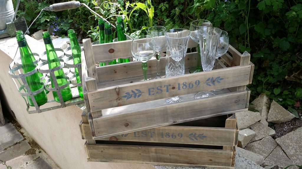 green stemmed glasses for wow woodland weddings in hire crates and green bottles in the background available to hire for weddings and events