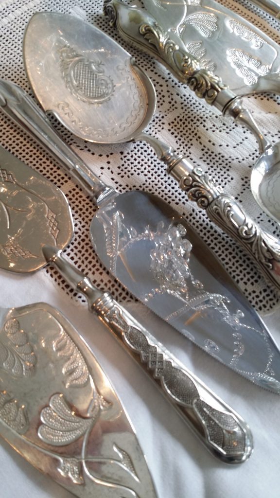 A detailed view of vintage silver etched cake slicers and knives