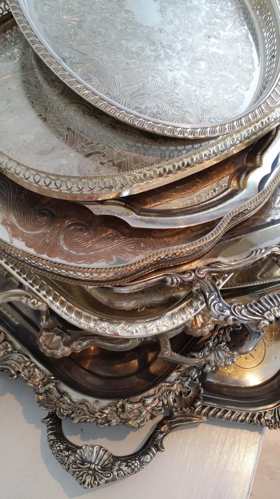 A stack of ornate silver vintage trays oval round and rectangle all available to hire