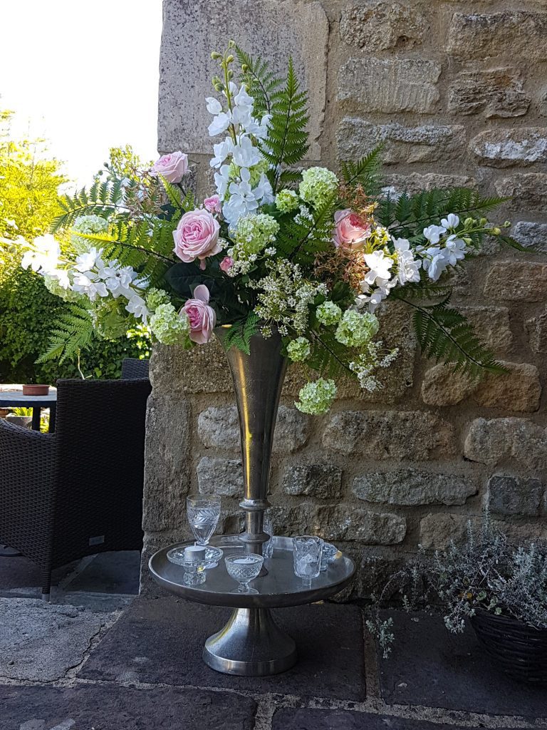 Silver Trumpet vase wedding floral centrepiece with cut crystal tealight holders and a flower arrangement with ferns, white and pink roses, white and green hydrangeas, gypsophila and white stocks with a silver lantern either side to hire