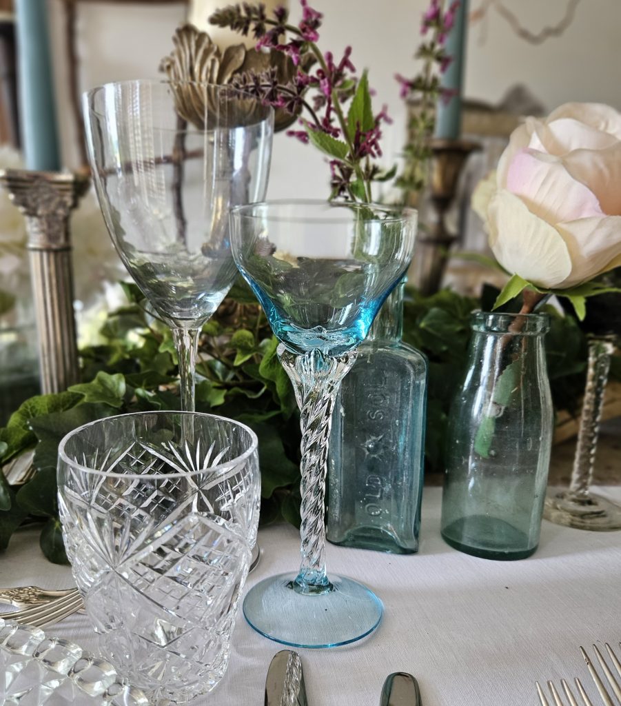 Twisted stem vintage small wine glass with a tint of blue next to a vintage cut glass water tumbler and delicate stem wine glass for hire
