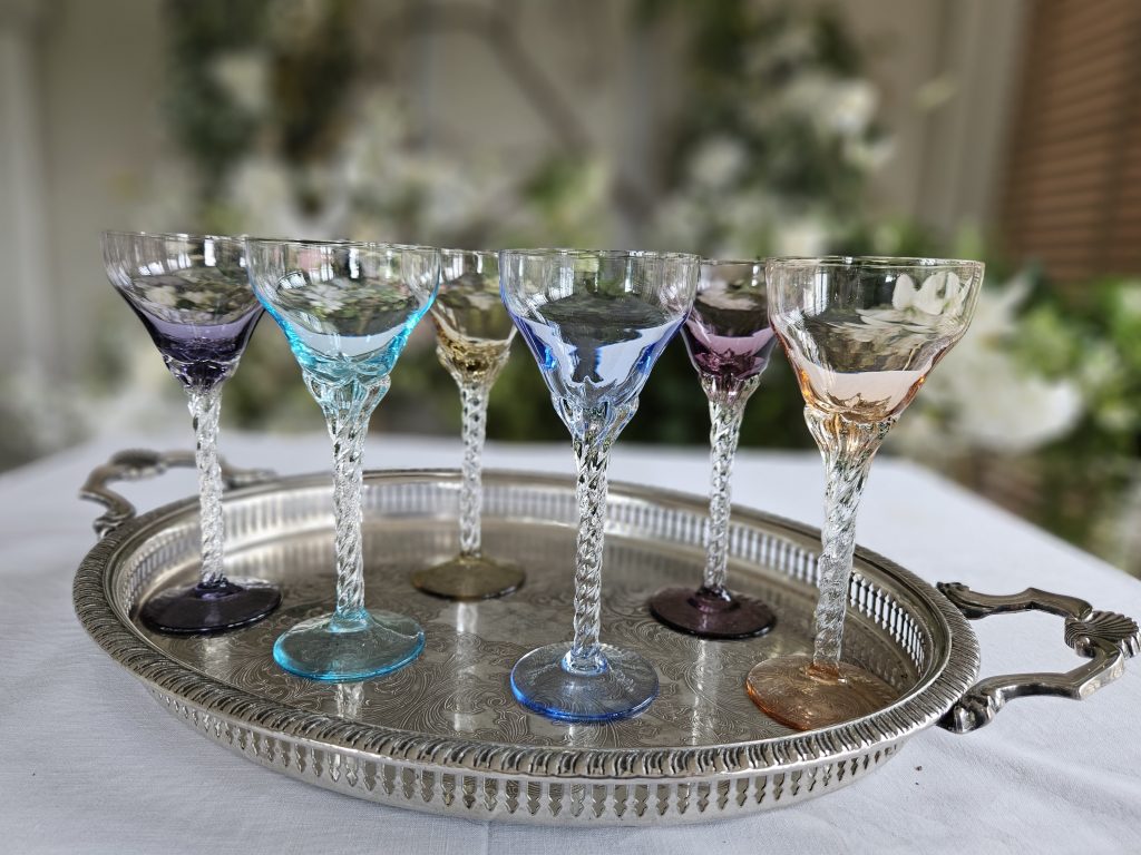 Twisted stem vintage small wine glasses in six different soft colours on a vintage silver tray for hire