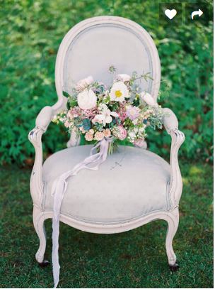 A vintage light grey embroidered chair with a white frame and a bouquet of blue, pink and white roses placed on it furniture available to hire