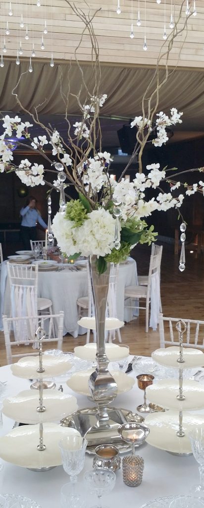 Silver ornate slim vase with white hydrangeas, twisted willow and blossom with hanging crystals as a centrepiece in the gillyflower at Elmore court in the Cotswolds for hire