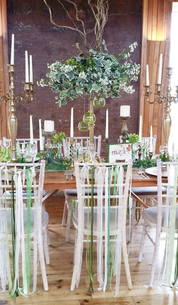 woodland wedding dressed table decorations with gold candelabras and ivy wreaths, ribbon chair backs at Elmore Court with tealight glass globes for hire