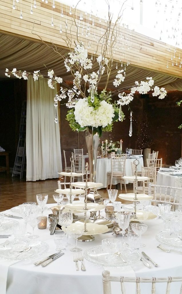 Silver ornate slim vase with white hydrangeas, twisted willow and blossom with hanging crystals as a centrepiece in the gillyflower at Elmore court in the Cotswolds