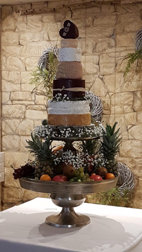 a grand layered three tiered silver cake stand. The bottom and middle layers are filled with grapes, peaches, apples and pears the top layer is a 8 tier cake built of different cheesesall available to hire