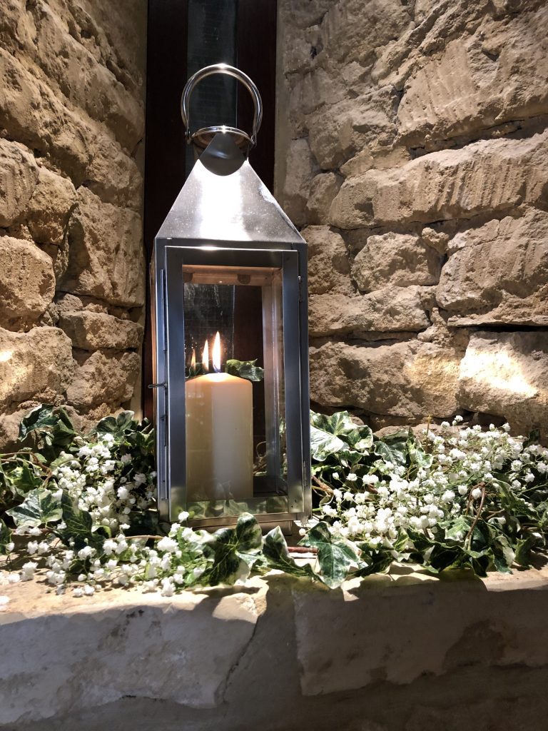 stylish silver lantern lit in an alcove at the great tythe barn in Tetbury with ivy and gypsophila wrapped round it for hire