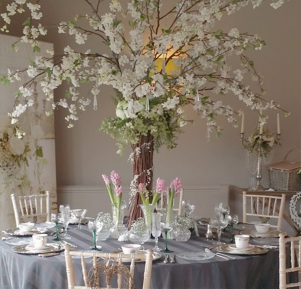 wedding styling table centrepiece with Twigs and blossom tree with cut crystal vases and vintage crockery, teacups and saucers and vintage glasses to hire