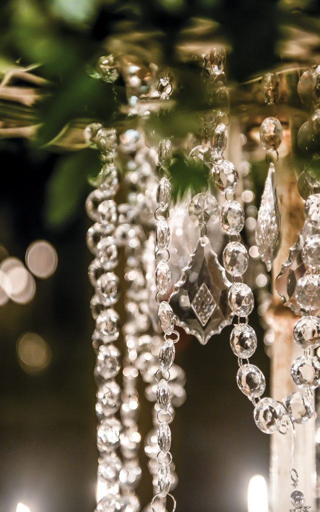 Close up of hanging crystals and diamante strings with a pendant hanging from a wreath of greenery for hire