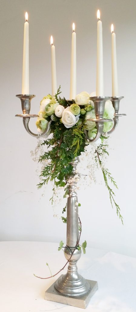 luxury silver candelabra with a garland of flowers at the centre and ivy and fake roses mixed in, available to hire for weddings and events