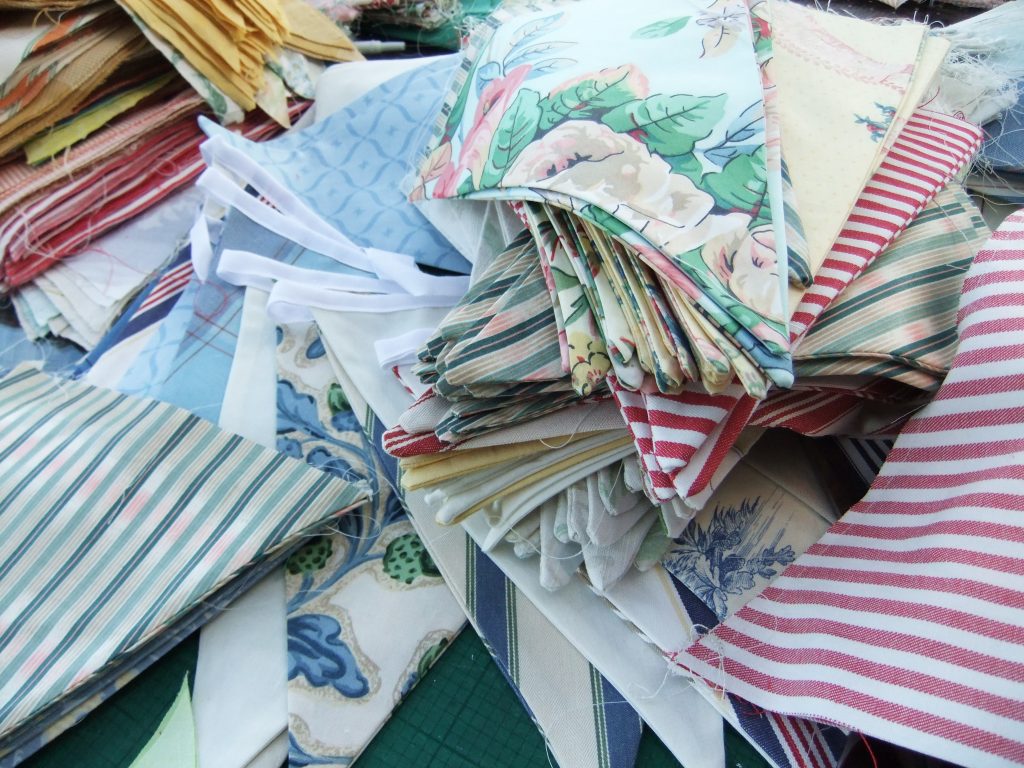 Bunting making and measuring the different flags and prints and patterns all stacked up, ready to be sown onto the string