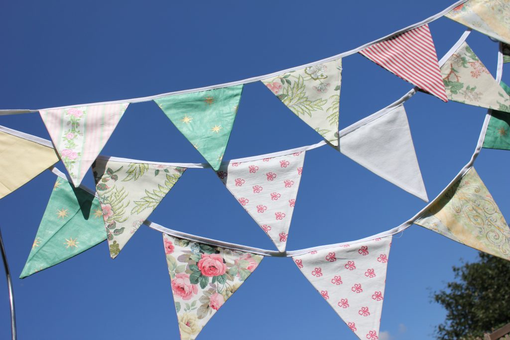 luxury garden party bunting in pastel colours and prints hanging in front of the blue sky