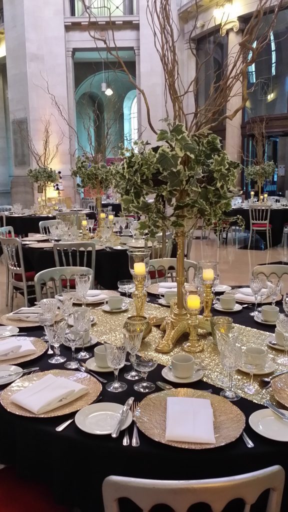 A Cardiff museum wedding with round tables and black tablecloths and a gold runner
