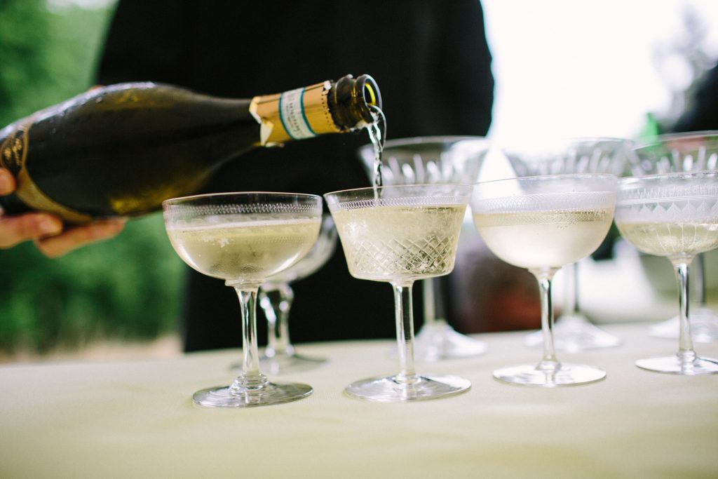 Vintage champagne saucers or vintage champagne coupes being filled with chilled prosecco