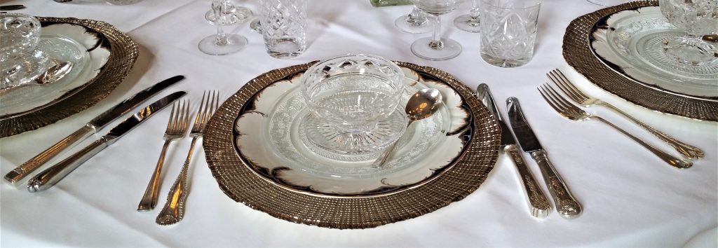 Vintage cutlery, gold charger plates, and vintage crockery as a place setting vintage glasses for wedding at Cowley Manor to hire