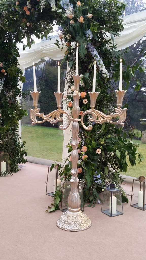 At cowley manor wedding fayre we set up our Stunning ornate extra large candelabra with pillar candles in front of a floral arch inside a marquee