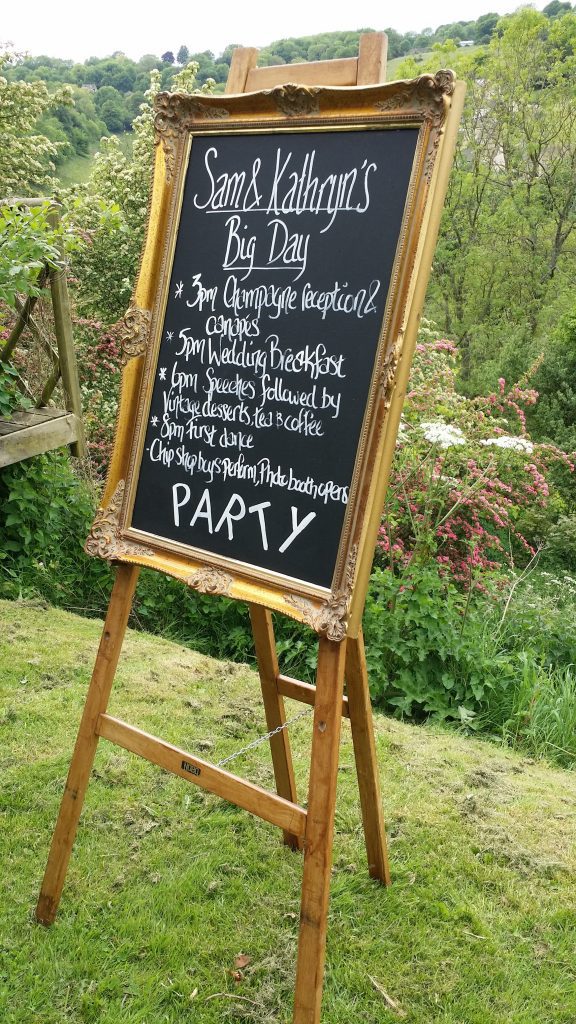 order of the day on a chalk board with a gold frame on a wooden easel for hire