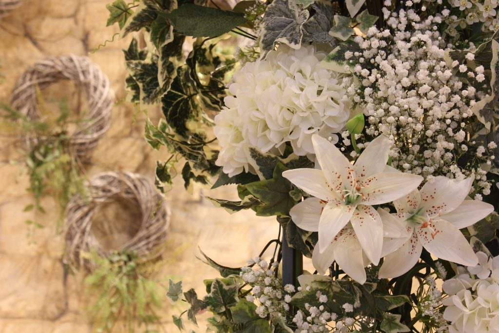 close up of Luxury quality faux flowers in whites and greens, with fresh gypsophila on one of our pillar arches available to hire