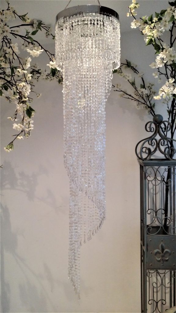 Crystal hanging waterfall chandelier with white blossom branches in the background for hire