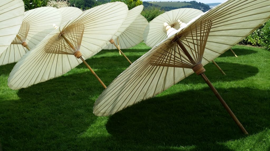 A close up of the underside of 5ft wide paper parasols with oriental bamboo spokes and centre pole. perfect for creating shade at a wedding or event 12 available for hire