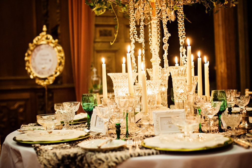 Fresh foliage wreath with ivy and hanging crystal chains centrepiece, with vintage glass vases and vintage glass candlestick and tealight holders and vintage wine, champagne and water glasses on a faux fur tablecloth to hire