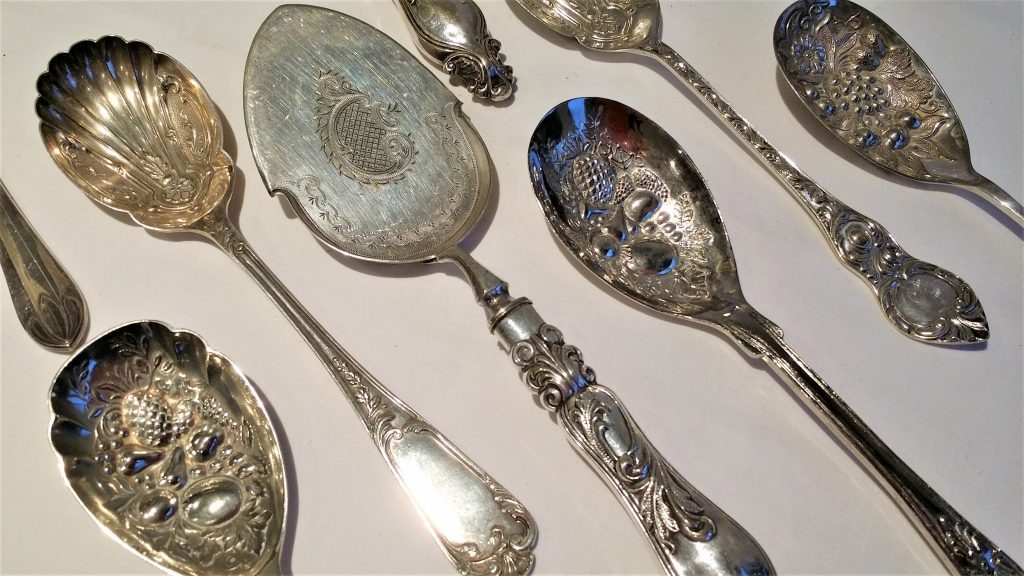 A close up of vintage ornate serving spoons including a fish cutter