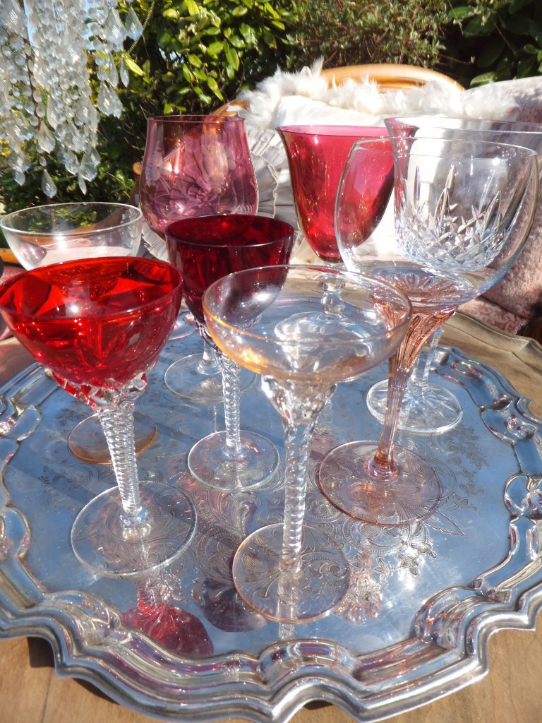 A silver tray of coloured wine glasses in reds pinks and peaches available to hire