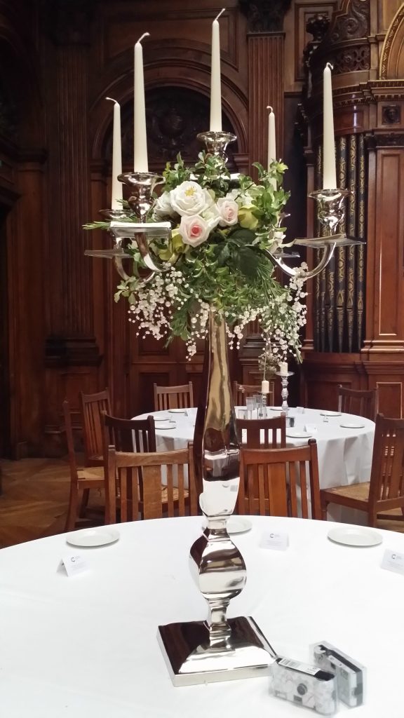 high shine extra large silver candelabra with a wreath of faux pink and white roses and fresh greenery with a string of pearls draping over the arms for hire