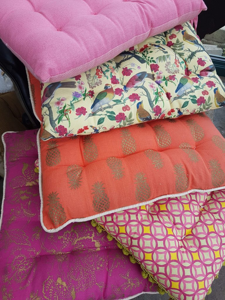 A stack of bright pinks oranges and patterned cushions for Viking chairs at a garden party to hire
