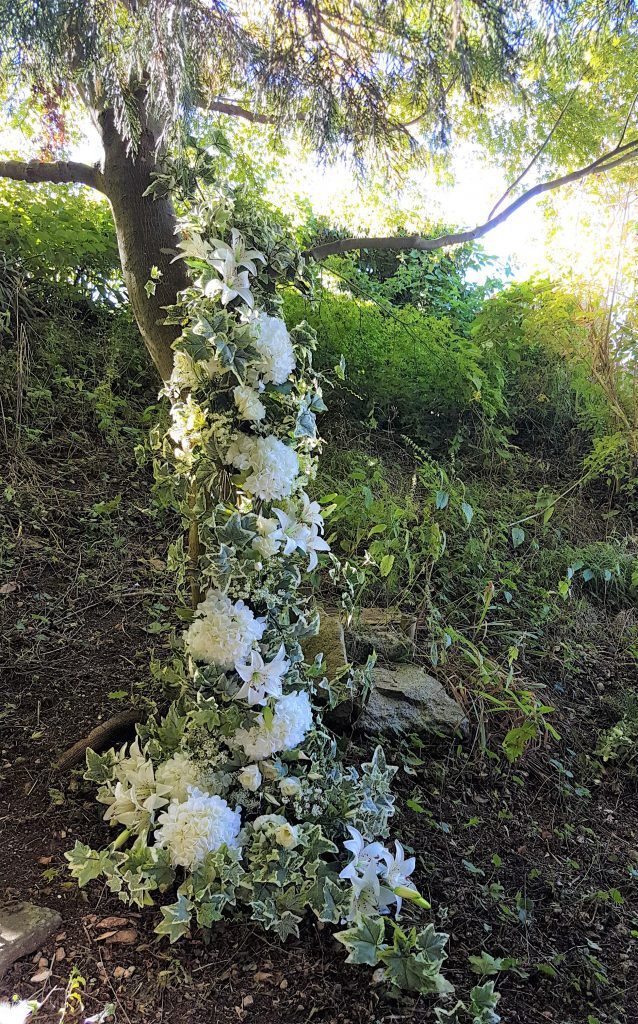 garland of wedding flowers draped in a tree as decor at a woodland wedding available to hire for weddings and events