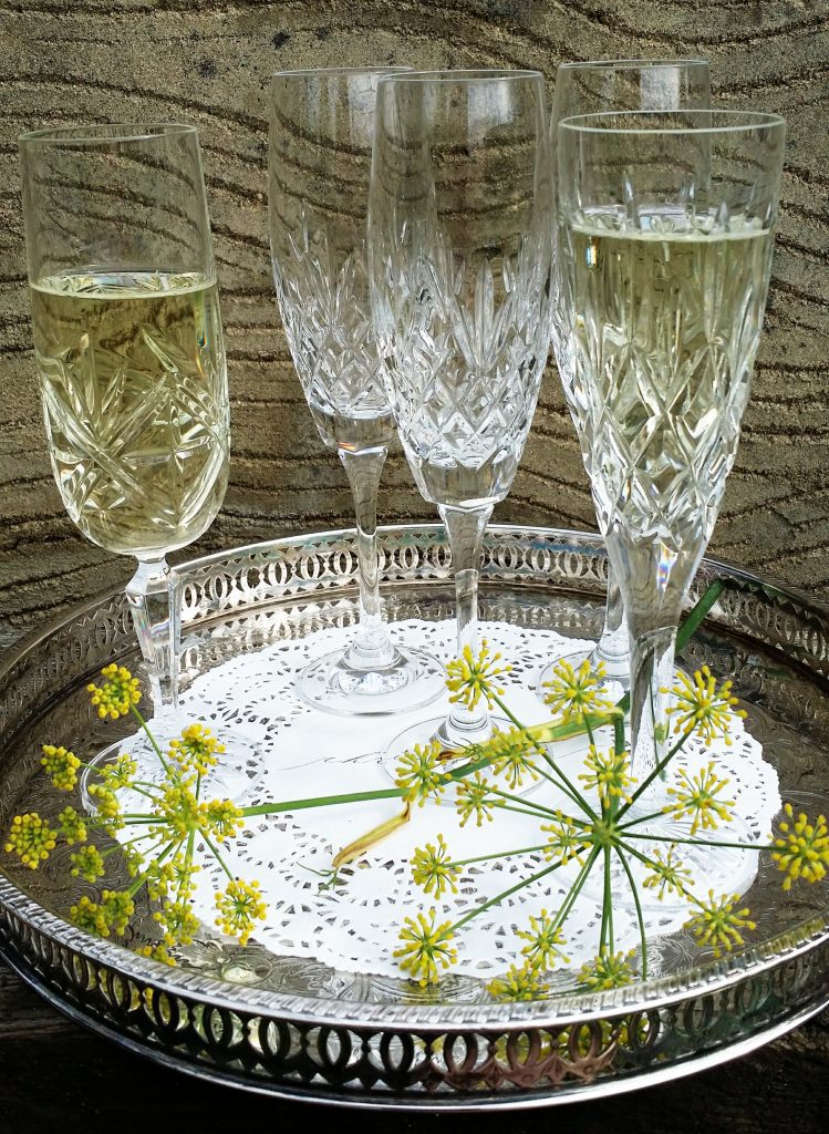 five cut crystal champagne glasses some filled with prosecco sat on a vintage silver tray for hire