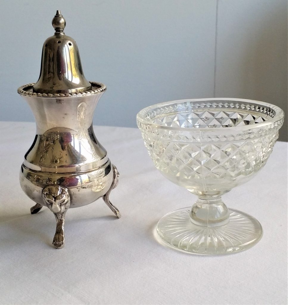 A product shot of a vintage silver pepper shaker and cut crystal glass salt pinch pot to hire