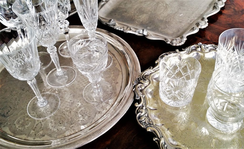 Cut crystal vintage wine glasses, water tumblers and champagne saucers, on ornate vintage silver trays