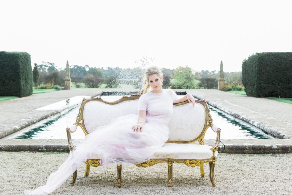 White and gold rococo vintage sofa at Sudeley castle with a bride sat across it