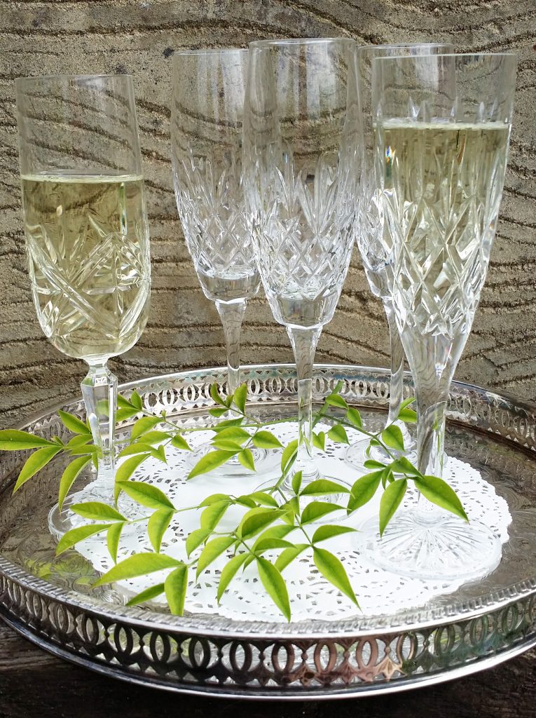 five cut crystal champagne glasses some filled with prosecco sat on a vintage silver tray for hire