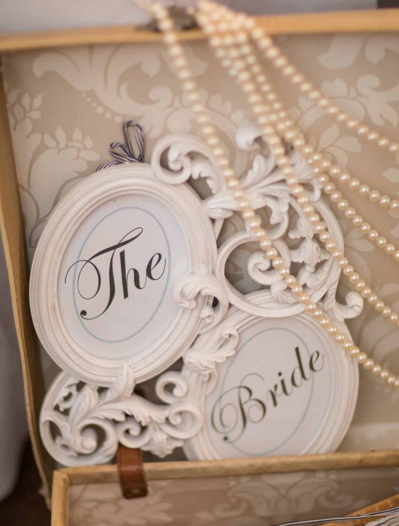 vintage suitcase with strings of pearls and an ornate frame with 'the Bride' in the frame
