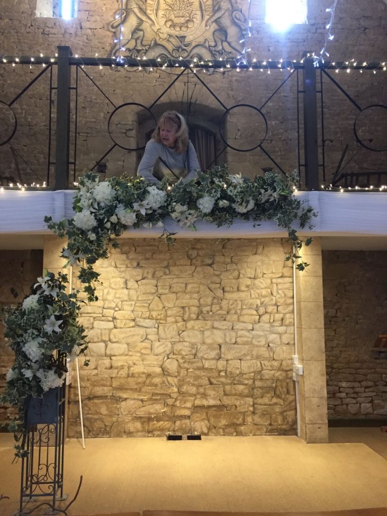 dressing the great Tythe barn with our faux flower garland and pillars to frame the bride and groom in the wedding ceremony