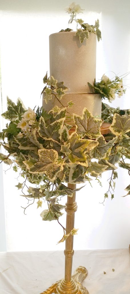 pedestal gold cake stand with a two tier cake wrapped in ivy for a luxury wedding, available for hire for weddings and events