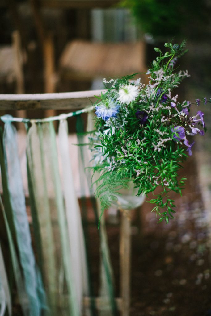 White and green ribbon chair back ties with a bunch of wild flowers for the aisle side available to hire for weddings and events