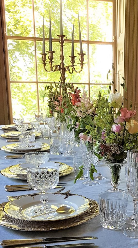 hire of vintage glasses cutlery ,plates gold chargers & gold candelabras. the crockery is layered up with a vintage cut crystal sundae dish sat on the top and a variety of wild flowers in the vases down the centre of the table.