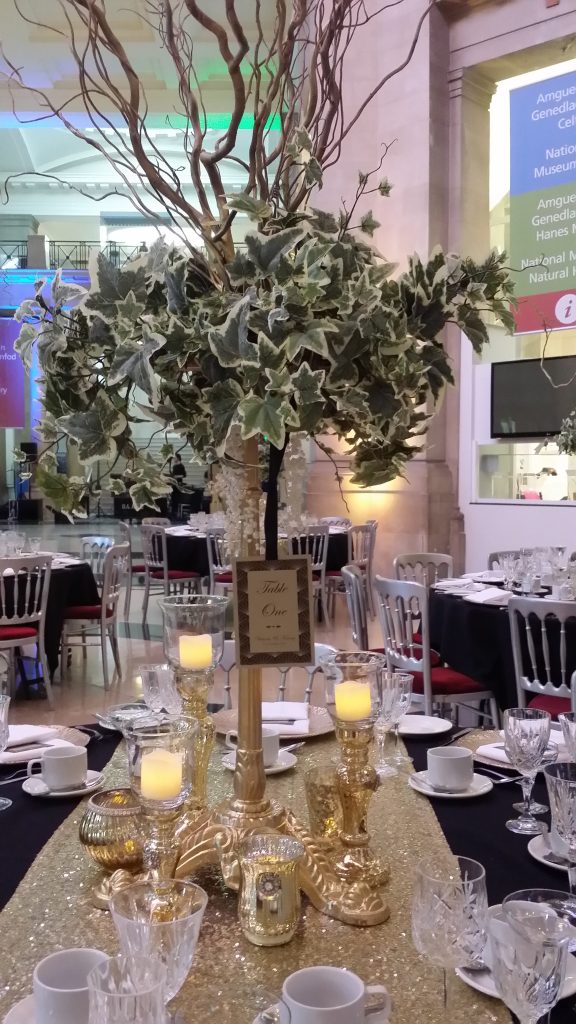 A Cardiff museum wedding with round tables and black tablecloths and a gold runner