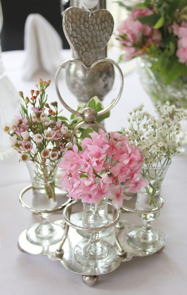 Silver vintage cruet with glass shot glasses with small bunches of wild flowers and gypsophila