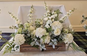 two wooden crates filled with luxury fake flowers in white and green sat side by side at the top of an aisle on a cream carpet runner